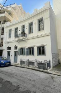 Biały budynek z samochodem zaparkowanym przed nim w obiekcie Piraeus art deco apartment w Pireusie