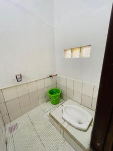La salle de bains est pourvue de toilettes et d'un seau vert. dans l'établissement Villa Situ Patenggang, à Ciwidey