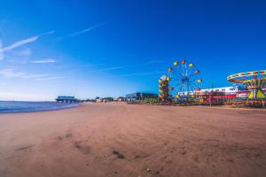 a beach with an amusement park and a ferris wheel at Dolphin Rooms in Cleethorpes