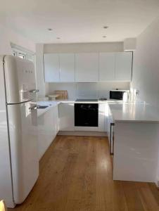 una cucina con armadietti bianchi e frigorifero bianco di Large 2 Bed Apartment London Catford Lewisham - Perfect for Long Stays a Londra