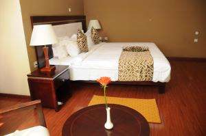 una habitación de hotel con una cama y una mesa con un jarrón en Melka International Hotel, en Addis Ababa