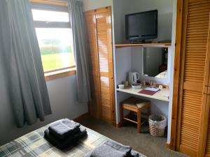 a bedroom with a bed and a tv and a window at Polrudden in Orkney