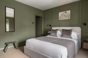a bedroom with a white bed with green walls at Bryony Cottage: Close to Station in Windermere