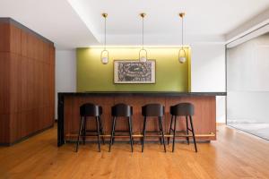 a bar in a room with three stools at Lumina at Taman Condesa in Mexico City