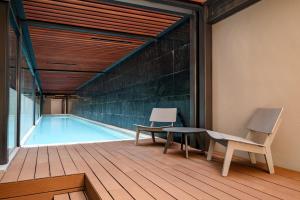 Dos sillas y una mesa junto a una piscina. en Lumina at Taman Condesa, en Ciudad de México 52 fotos más