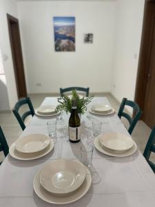 a table with white plates and a bottle of wine at Coral Cove Comfort Room 2 in St Paul's Bay