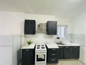 a kitchen with a stove and a white refrigerator at Coral Cove Comfort Room 2 in St Paul's Bay