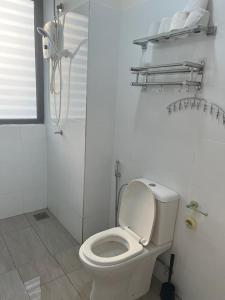 La salle de bains blanche est pourvue d'une douche et de toilettes. dans l'établissement Yuyu Star Suites, à Kampong Bekoh