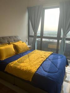 - un lit avec une couette jaune et bleue et une fenêtre dans l'établissement Yuyu Star Suites, à Kampong Bekoh