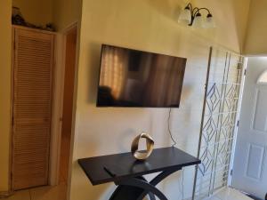 a table in a room with a tv on the wall at Charming 2-Bed House in Portmore gated community in Portmore