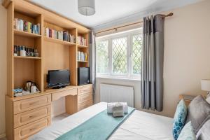 um quarto com uma cama, uma televisão e uma janela em Ross House em Black Notley