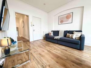 a living room with a blue couch and a glass table at 2 Bed- Muswell Hill- City Views! in London