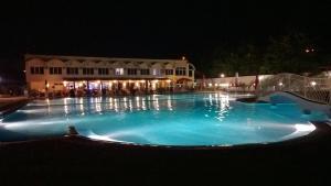 Una gran piscina azul por la noche en Hotel Mimoza, en Razgrad