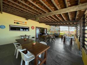 uma sala de jantar com mesas e cadeiras de madeira em Pousada Parracho em Maracajaú