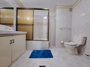 a bathroom with a toilet and a shower and a blue rug at Departamento ejecutivo en el corazón de San Miguel in La Paz