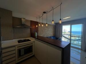 uma cozinha com um balcão com um fogão e uma janela em Apartamento Vista Mar aconchegante no Rio Vermelho em Salvador