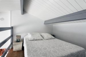 een witte slaapkamer met een bed en een plafond bij Maison Rhéa in Rivedoux-Plage