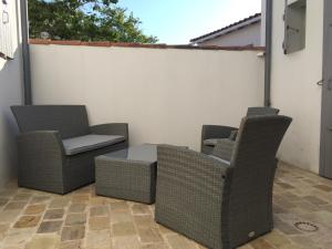 2 rieten stoelen en een tafel op een patio bij Maison Rhéa in Rivedoux-Plage