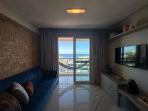 sala de estar con sofá azul y ventana grande en Apartamento Vista Mar aconchegante no Rio Vermelho en Salvador