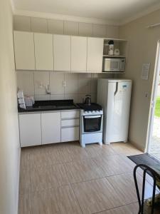 a small kitchen with white cabinets and a refrigerator at Residencial Cecilia Cruz in Bombinhas