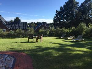 three park benches sitting in a grassy area with trees at Hotel Garni Sössaarep's Hüs in Nebel