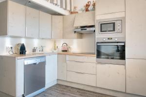 een keuken met witte kasten en een magnetron bij PERTUIS appartement tout confort in Landrais