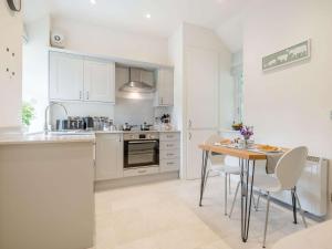 a kitchen with white cabinets and a table and chairs at 1 Bed in Brecon 88748 in Aber-Brân