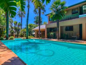 a swimming pool in front of a house with palm trees at GSpot94 in Johannesburg