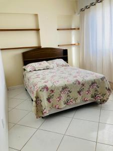 een slaapkamer met een bed met een bloemdekbed bij Residencial Imperatriz in Balneário Camboriú