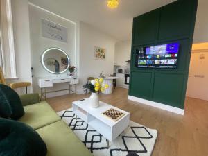 a living room with a green cabinet with a tv at Clacton Chic in Clacton-on-Sea