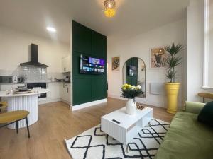 a living room with a green cabinet and a kitchen at Clacton Chic in Clacton-on-Sea
