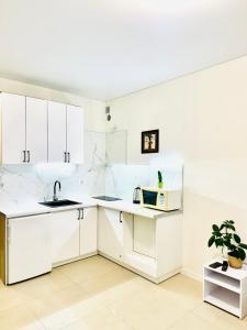 a white kitchen with a sink and a microwave at Тут светло и уютно in Kyiv +15 photos