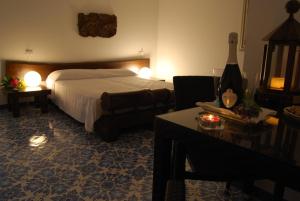 a hotel room with a bed and a table with a bottle of wine at B&B Il Resort Dell'Artista in Venetico +56 photos