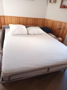 uma cama com lençóis brancos e almofadas num quarto em Les Terrasses de la Foux Coquet studio 100m Labrau 4 couchages em La Foux