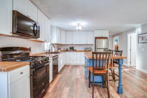 una cucina con armadi bianchi e tavolo con sedie di New Hampshire Getaway with Game Room and Lake Access 