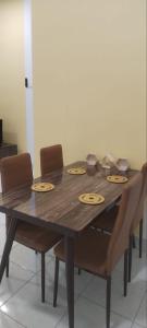 uma mesa de madeira com quatro cadeiras à volta em JM Homestay Youth City Nilai em Nilai