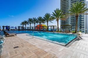a swimming pool with palm trees and a building at 2 bed rental on the beach15th floor Hollywood Miami in Hallandale Beach