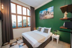 特拉維夫的住宿－INTA Hotel，一间卧室配有一张带绿色墙壁的床