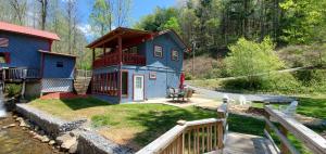 een blauw huis met een veranda en een terras bij Waterwheel Cabin by the Creek in Murphy