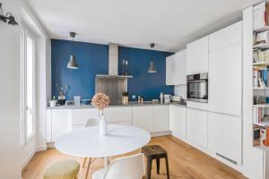 eine weiße Küche mit blauen Wänden und einem weißen Tisch in der Unterkunft Nice T3 near Lake Saint-Mandé - Welkeys in Saint-Mandé