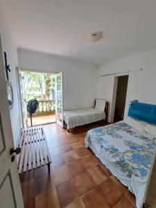 a bedroom with a bed and a bench and a window at Casa Pé na Areia Cantão do Bora Bora - Manaaki Surf Hostel in São Sebastião