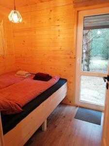 Bett in einem Holzzimmer mit Fenster in der Unterkunft Świetna Chatka in Świętne