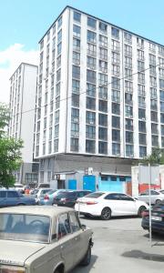 a large white building with cars parked in a parking lot at Тут светло и уютно in Kyiv