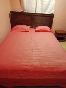 ein rotes Bett mit zwei roten Kissen darauf in der Unterkunft Vacances agréables c'est ici in Les Abymes