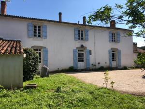 una vecchia casa bianca con finestre blu e un cortile di Maison typique/SPA/ Wifi/20 min plage a La Jonchère