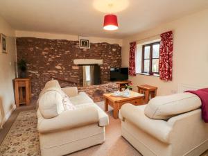 a living room with two chairs and a brick wall at Barn Owl in Clatworthy