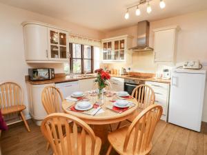 a kitchen with a table and chairs and a white refrigerator at Barn Owl in Clatworthy
