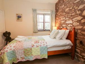 a bedroom with a bed and a stone wall at Barn Owl in Clatworthy