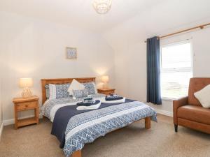 a bedroom with a bed and a chair and a window at Bythynnod Newydd in Trefor