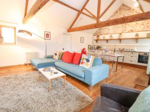 a living room with a blue couch and a table at Packway Barn in Halesworth